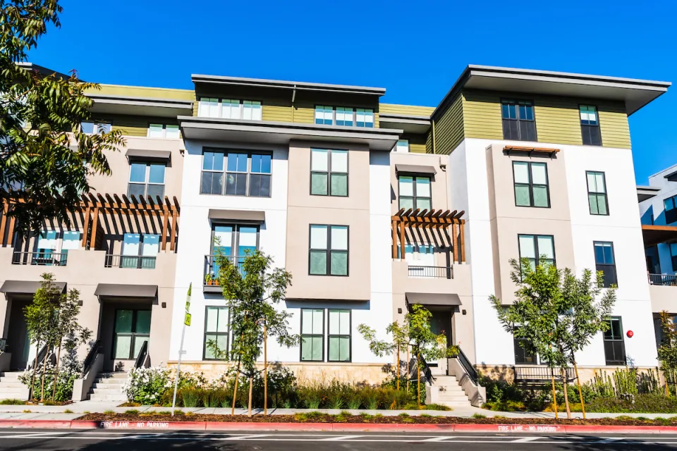 Four-story light-colored multifamily apartment building.